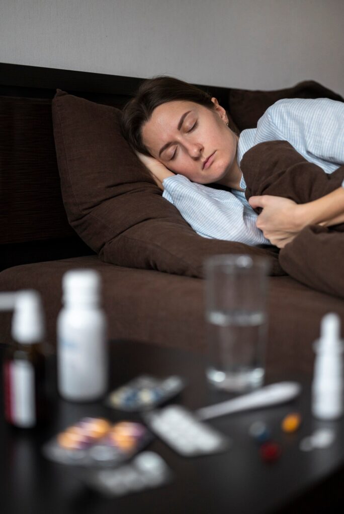 A woman laying asleep on a bed with medications in the foreground