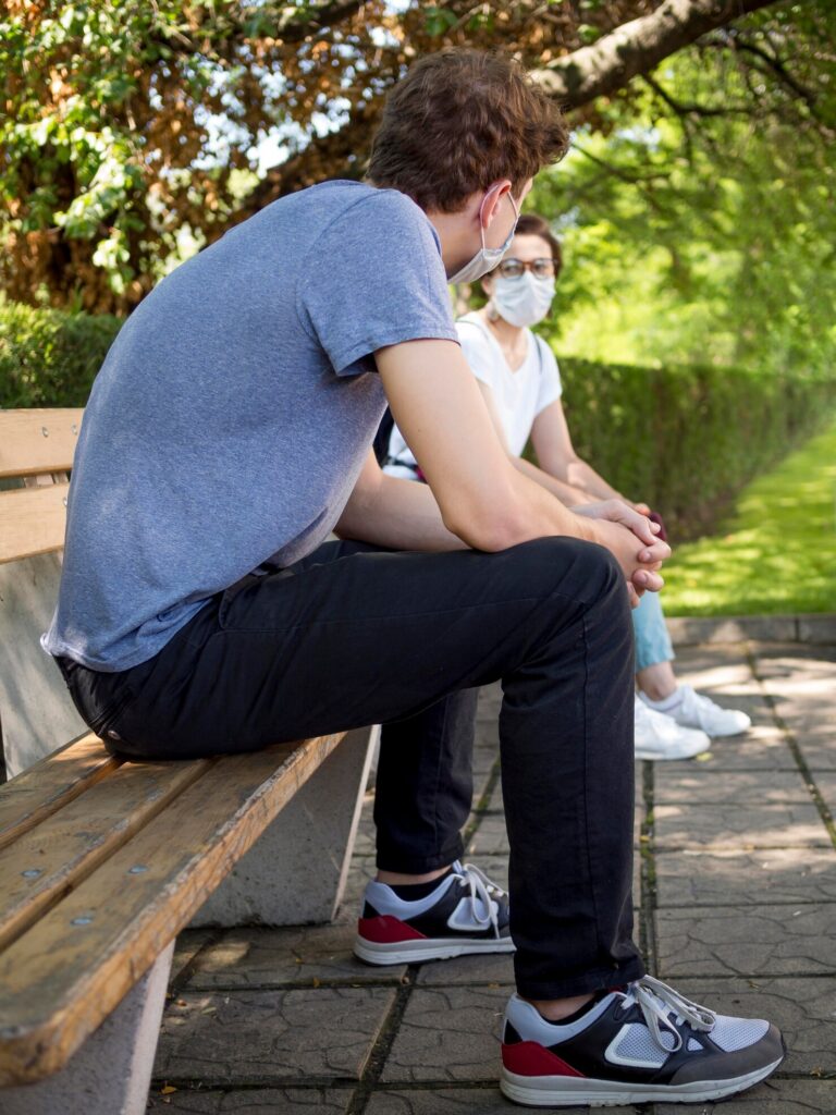 Young adults sitting on a park bench talking